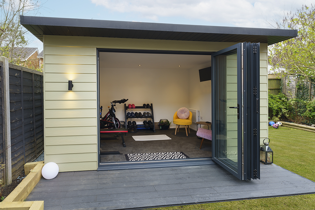 A small backyard garden room with an open door, inviting natural light and showcasing greenery outside.